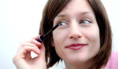 Beautiful young woman applying mascara