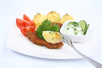 Mashed potatoes on a fork, with pork chop and vegetable