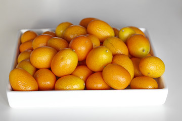 Kumquats piled on a white ceramic tray