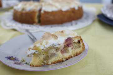Slice of rhubarb cake with meringue topping on white plate