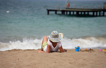 woman in hat sitting on the beach