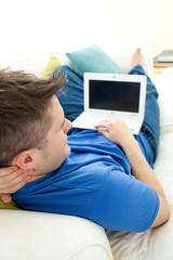 Charming manusing a laptop on a sofa