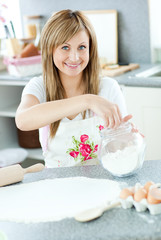 Obraz na płótnie Canvas Portrait of a cheerful woman preparing a cake in the kitchen