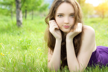 Naklejka na ściany i meble young brunette teenager girl lying on meadow