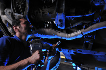 Fototapeta Dramatically lightened mechanic working under a car obraz