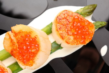 Grilled sea scallops with asparagus in a black plate