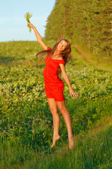 Jumping pretty brunette girl against summer meadow