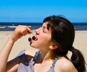 Young woman on the beach with two cherry