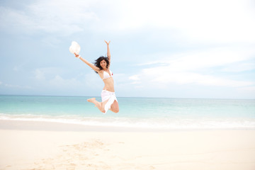 happy young woman jumping in the beach
