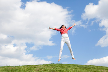 pretty young woman jumping on green grass