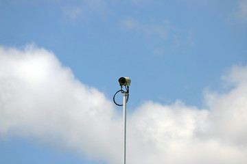 Face on security camera in cludy blue sky background.