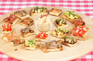 Various italian bruschetta over a wooden cutting board