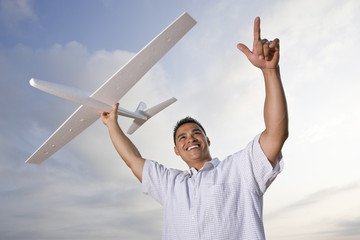 Hispanic man holding model airplane glider over head