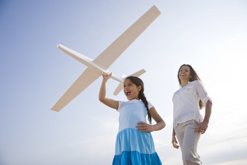 Mother and daughter having fun with toy plane