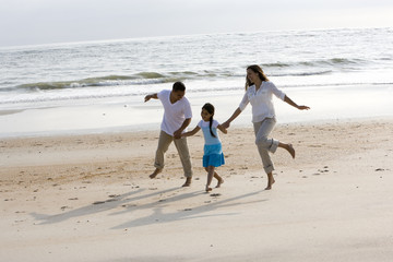 Fototapeta na wymiar Hispanic family holding hands skipping on beach
