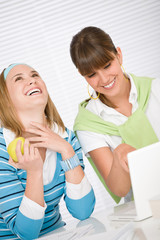 Student at home - two happy young woman with laptop