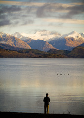 Man viewing mountains at sunrise with Lake Wanaka in foreground in New Zealand