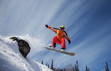 Naklejka na ściany i meble Snowboarder skoki w powietrzu z błękitne niebo w tle