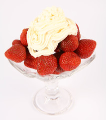 Strawberries in a glass cup with whipped cream  in close up