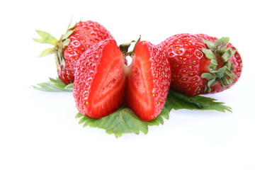 Strawberries on a leaf, one cut in half, on white background