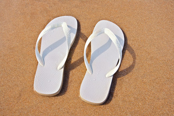 white flip flops on sand beach