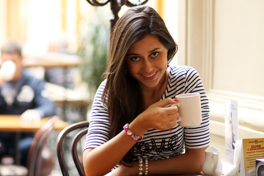 Beautiful young girl sipping coffee