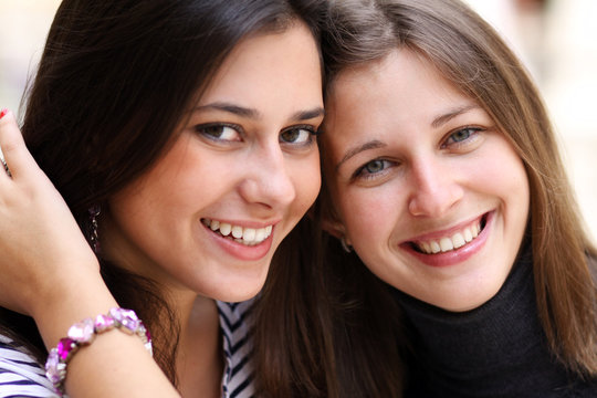 Closeup portrait of two happy pretty teenagers embracing
