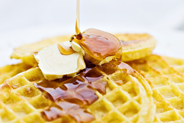 Syrup being poured over golden delicious waffles. © Stephanie Frey
