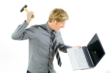 wütender Mann schlägt mit Hammer auf Notebook