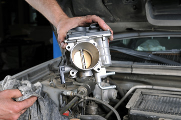 Car mechanic repairing a part of engine.