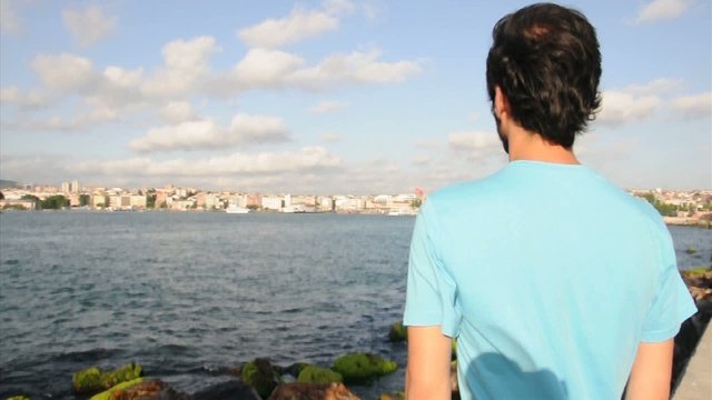 man with blue t shirt waiting by sea side