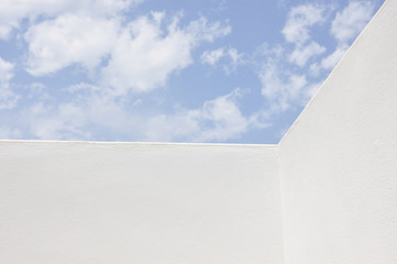 Weiße Wandecke vor blauem Himmel mit Wolken