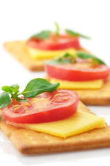 Fototapeta na wymiar Crackers with cheese, tomato and basil