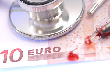 Blut in Spritze und Stethoskop mit 10 Euroschein