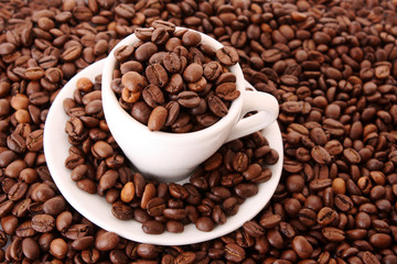 Small white cup of coffee with coffee grain on grain background