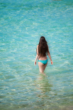 The beautiful girl in blue bikini costs in transparent sea water