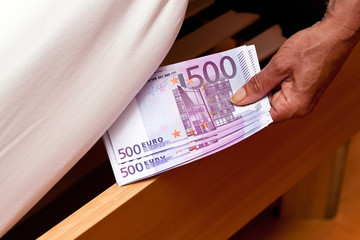 Euro Geldscheine werden unter dem Bett versteckt.