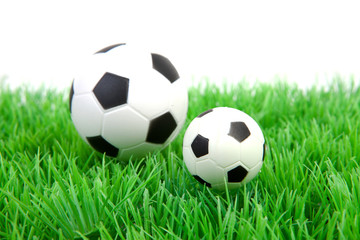 Two soccer balls on grass over white background