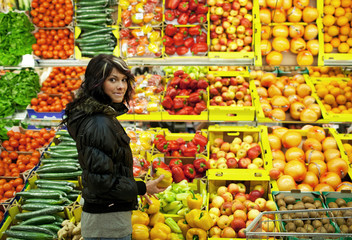 Beautiful young woman buying fruits and vegetables at a supermar