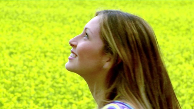 zoom da viso di ragazza che si gira in un prato fiorito