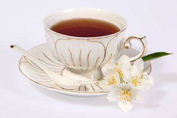 Cup of tea with jasmine flowers isolated on white.