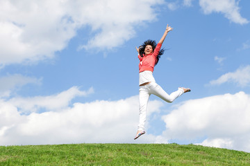 pretty young woman jumping on green grass