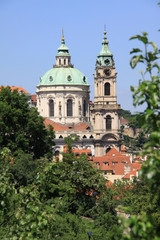 Fototapeta na wymiar View on Prague's St. Nicholas' Cathedral with flowering trees