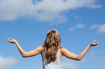 Fototapeta na wymiar Peaceful young woman meditating against a blue sky