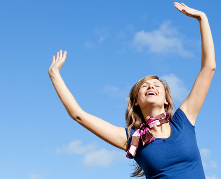 Delighted blond woman punching tha air against blue sky