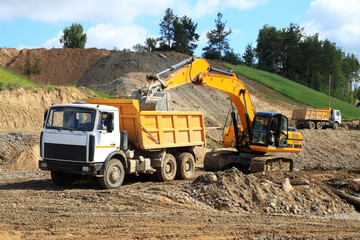Fototapeta premium Backhoe loader loading dumper