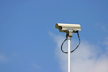 Security camera in cloudy blue sky background.