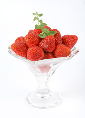 Strawberries in a glass cup with a lemon balm twig