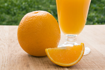 Orange and fresh orange juice on green leaves background