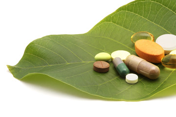 vitamins pills and tablets on green leaf